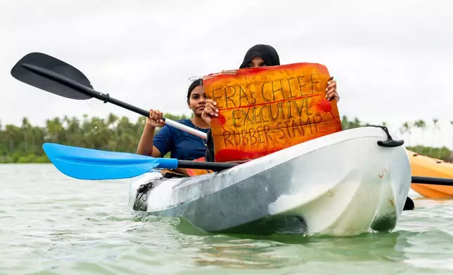 A participant holds a sign as part of Project ThimaaVeshi, a youth-led demonstration against ongoing reclamation project damaging mangroves off the coast of Addu City, Maldives, June 3, 2026. (AP Photo/Sophia Nasif)