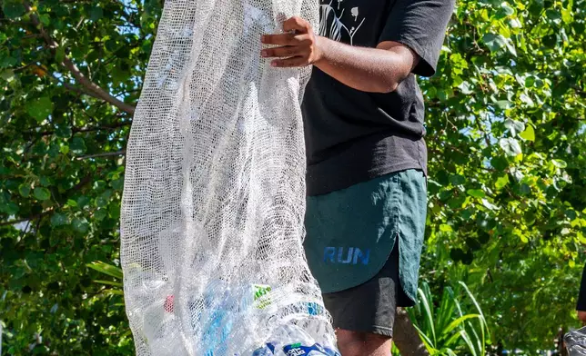 Mohamed Ma'al Nazeel, co-founder of Ripple, a youth led group, empties out his full bag of plastic waste collected during a joint plastic pollution clean-up in Male, Maldives, June 19, 2026. (AP Photo/Sophia Nasif)