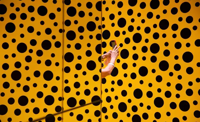 FILE -A woman takes a photo during her visit at the art work 'The Spirits of the Pumpkins Descended into the Heavens' by Yayoi Kusama, part of retrospective exhibition in the Tel Aviv Museum of Art, Israel, Monday, Nov. 15, 2021. (AP Photo/Oded Balilty, File)