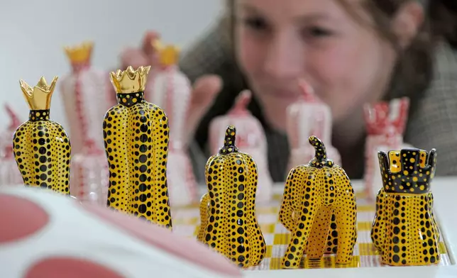 FILE - Exhibition assistant Kathrin DuBois of the Museum Ludwig in Cologne arranges chess board figures of the Japanese artist's Yayoi Kusama installation 'Pumpkin Chess' in the Porzellanikon Museum in Selb, southern Germany, on Thursday, April 22, 2010. (AP Photo/Jens Meyer, File)
