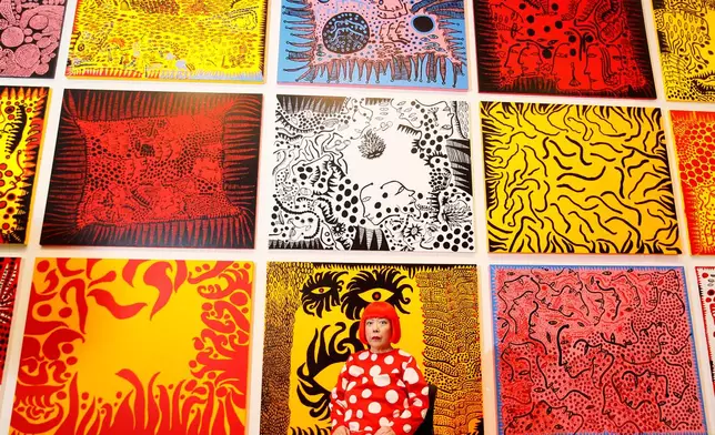 FILE - Japanese artist Yayoi Kusama poses for photographers in front of her painting 'Love Arrives at the Earth Carrying with it a Tale of the Cosmos', center bottom, and other paintings at the Tate Modern in London, Tuesday, Feb. 7, 2012.(AP Photo/Kirsty Wigglesworth, File)