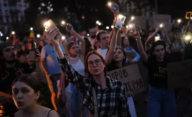 People sing and hold up their cell phone flashlights during a rally to protest the dismissal of Mykhailo Fedorov as Ukraine's Defense Minister in Kyiv, late Sunday, Aug. 16, 2026. (AP Photo/Francisco Seco)