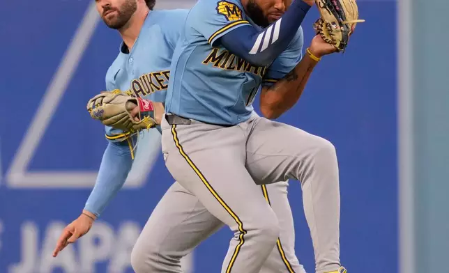 Milwaukee Brewers center fielder Garrett Mitchell, left, makes a catch on a ball hit by Los Angeles Dodgers' Shohei Ohtani as left fielder Jackson Chourio almost collides with him during the first inning of a baseball game Friday, Aug. 14, 2026, in Los Angeles. (AP Photo/Mark J. Terrill)