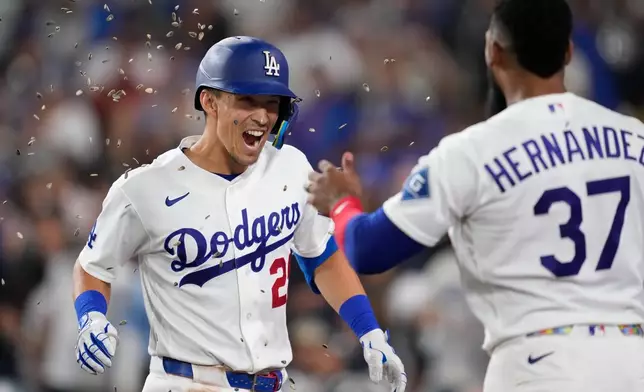 Los Angeles Dodgers' Tommy Edman, left, has seeds thrown at him by Teoscar Hernández after hitting a solo home run during the sixth inning of a baseball game against the Milwaukee Brewers, Friday, Aug. 14, 2026, in Los Angeles. (AP Photo/Mark J. Terrill)