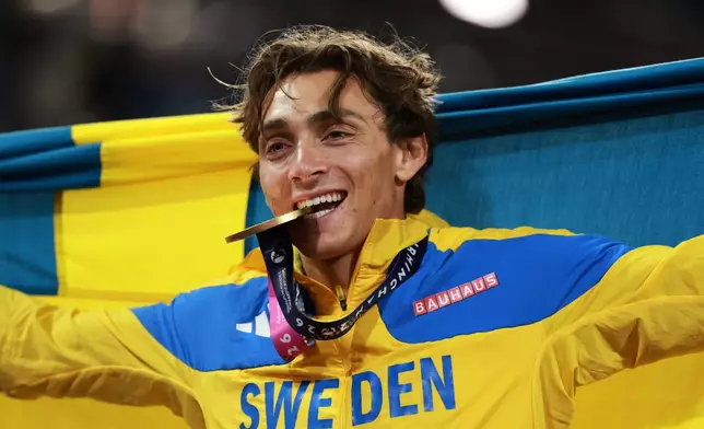 Sweden's Armand Duplantis bites his gold medal as he celebrates winning the men's pole vault final at the European Athletics Championships in Birmingham, England, Sunday, Aug. 16, 2026. (AP Photo/Morgan Harlow)