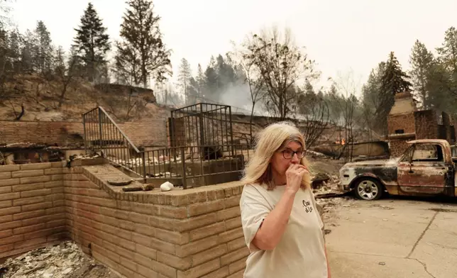 Kimberley Sather stands at the duplex she rents on W. Indian Trail Rd. after it burned in a wildfire in Spokane, Wash., Sunday, Aug. 2, 2026. (AP Photo/Young Kwak)