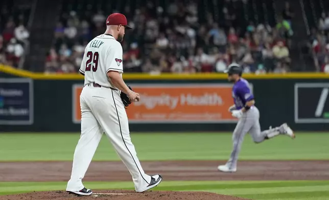 Arizona Diamondbacks starting pitcher Merrill Kelly (29) gets a new baseball after giving up a three-run home run to Colorado Rockies' Brett Sullivan, right, during the second inning of a baseball game, Wednesday, Aug. 12, 2026, in Phoenix. (AP Photo/Ross D. Franklin)