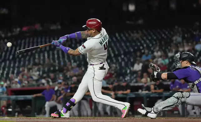 Arizona Diamondbacks' Ketel Marte (4) hits a run-scoring single as Colorado Rockies catcher Brett Sullivan reaches for the ball during the first inning of a baseball game, Wednesday, Aug. 12, 2026, in Phoenix. (AP Photo/Ross D. Franklin)