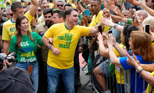 Opposition presidential candidate Flavio Bolsonaro and his wife, Fernanda Bolsonaro, greet supporters as they arrive for a presidential election campaign rally in Rio de Janeiro, Brazil, Sunday, Aug. 16, 2026. (AP Photo/Silvia Izquierdo)