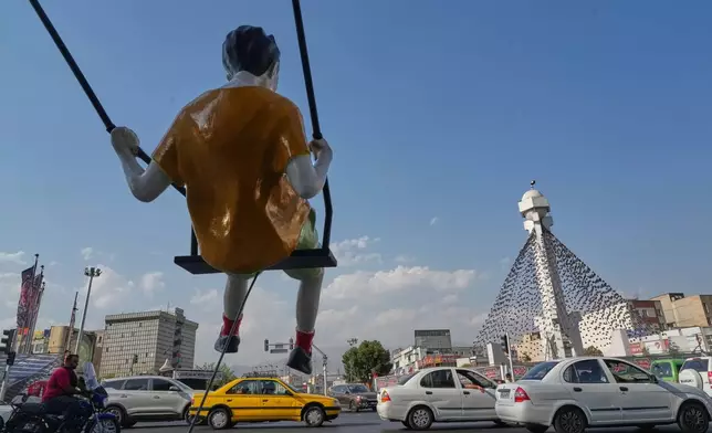 Vehicles drive past a statue of a swinging boy at a square in Tehran, Iran, Monday, Aug. 10, 2026. (AP Photo/Vahid Salemi)