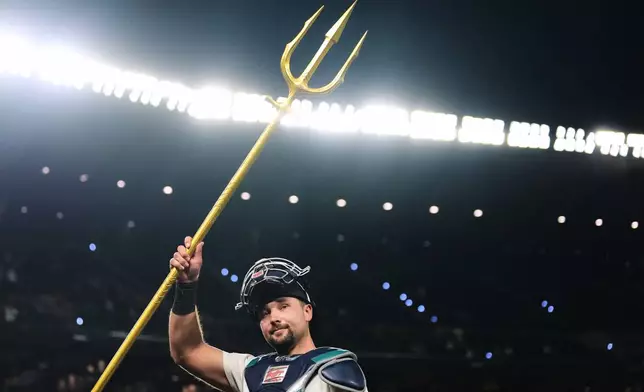 Seattle Mariners catcher Cal Raleigh lifts the trident to celebrate a win over the Philadelphia Phillies in a baseball game, Monday, Aug. 24, 2026, in Seattle. (AP Photo/Lindsey Wasson)