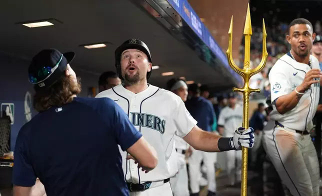 Seattle Mariners' Cal Raleigh, center, reacts after accidentally jumping into the ceiling of the dugout while celebrating his solo home run with pitcher Bryce Miller, left, during the seventh inning of a baseball game against the Philadelphia Phillies, Monday, Aug. 24, 2026, in Seattle. (AP Photo/Lindsey Wasson)