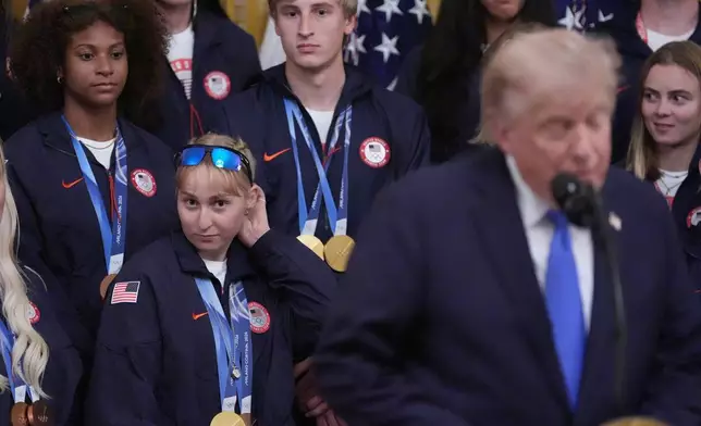 President Donald Trump speaks as Elizabeth Lemley, lower center, and Jordan Stolz, top center, watch, during an event for Olympic athletes, coaches, staff, and representatives from Team USA in the East Room of the White House, Thursday, Aug. 6, 2026, in Washington. (AP Photo/Alex Brandon)