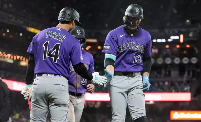 Colorado Rockies' Zac Veen (13) is congratulated by Ezequiel Tovar (14) after hitting a two-run home run that also scored Connor Norby, rear, during the sixth inning of a baseball game against the San Francisco Giants, Friday, Aug. 14, 2026, in San Francisco. (AP Photo/Jeff Chiu)
