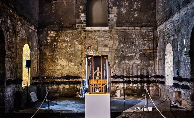 The organ, center, of the John Cage Organ Project Halberstadt is illuminated prior to a chord change of the organ inside the medieval Burchardi Church in Halberstadt, Germany, Wednesday, Aug. 5, 2026. (AP Photo/Markus Schreiber)