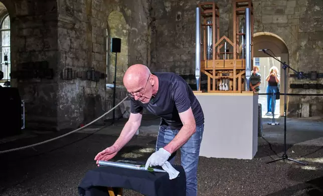 Kay Lautenbach of the board of the John Cage Organ Project Halberstadt of the prepares a new pipe prior to a chord change of the organ inside the medieval Burchardi Church in Halberstadt, Germany, Wednesday, Aug. 5, 2026. (AP Photo/Markus Schreiber)