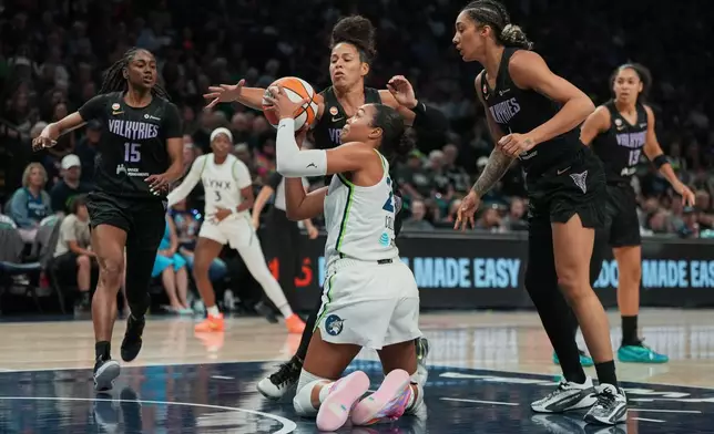 Minnesota Lynx forward Napheesa Collier, center front, controls the ball as Golden State Valkyries guard Veronica Burton, center top, defends during the first half of a WNBA basketball game Monday, Aug. 24, 2026, in Minneapolis. (AP Photo/Abbie Parr)