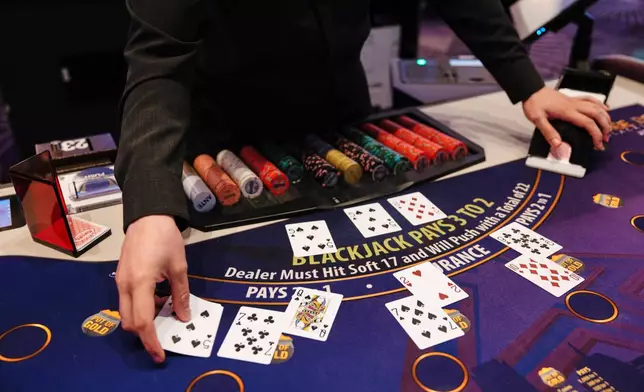 William Eary, a table games dealer at Harrah's Casino, shuffles a deck of cards at the casino in Chandler, Okla., Wednesday, Aug. 5, 2026. (AP Photo/Brittany Bendabout)