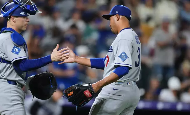 Los Angeles Dodgers catcher Hunter Feduccia, left, congratulates relief pitcher Edwin Díaz after defeating the Colorado Rockies in a baseball game Monday, Aug. 17, 2026, in Denver. (AP Photo/David Zalubowski)