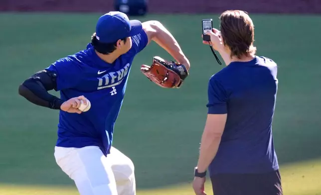 Los Angeles Dodgers' Shohei Ohtani warms up with a trainer prior to a baseball game against the Pittsburgh Pirates, Friday, Aug. 21, 2026, in Los Angeles. (AP Photo/Mark J. Terrill)