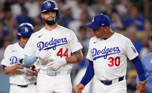 Los Angeles Dodgers' Andy Pages, walks to first with manager Dave Roberts after being hit by a pitch during the third inning of a baseball game against the Pittsburgh Pirates, Friday, Aug. 21, 2026, in Los Angeles. (AP Photo/Mark J. Terrill)