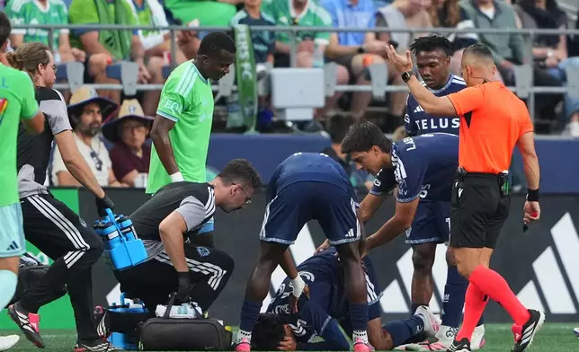 Vancouver Whitecaps midfielder Jeevan Badwal is checked for a concussion as Seattle Sounders defender Nouhou Tolo, third from left, looks on during the first half of an MLS soccer match against the Seattle Sounders, Sunday, Aug. 16, 2026, in Seattle. (AP Photo/Lindsey Wasson)