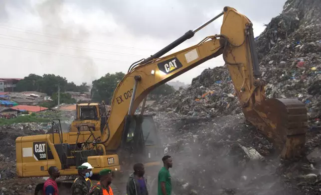 Rescue workers search through a heap of refuse after it collapsed at Conakry’s largest landfill, Guinea, Sunday, Aug. 23, 2026. (AP Photo/Fodo Toure)