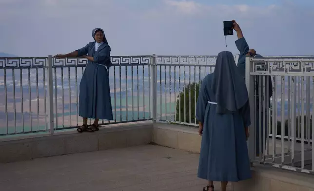 Nuns pose for photograph with the view from the Basilica of the Transfiguration on Mount Tabor, northern Israel, Aug. 6, 2026. (AP Photo/Ariel Schalit)