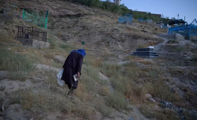Sima collects discarded items from the ground at a cemetery to reuse or sell in Kabul, Afghanistan, Wednesday, Aug. 12, 2026. (AP Photo/Nava Jamshidi)