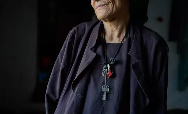 With a set of keys hanging around her neck, Sima, who believes she is about 60 years old but does not know her exact age, stands in the natural light from a window at her home in Kabul, Afghanistan, Wednesday, Aug. 12, 2026. (AP Photo/Nava Jamshidi)