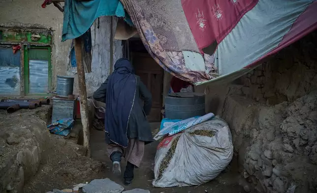 Sima enters her room at her home, where mud-brick walls and fabric coverings frame the entrance, in Kabul, Afghanistan, Tuesday, Dec. 3, 2024. (AP Photo/Nava Jamshidi)