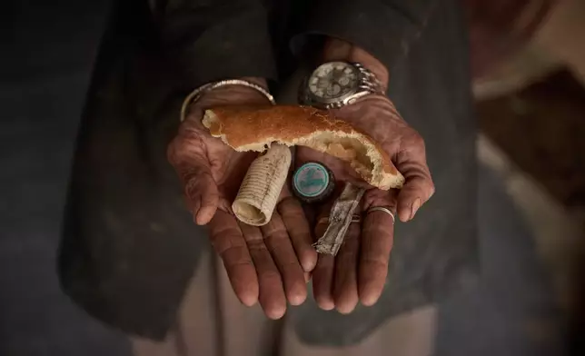 Sima holds discarded items, including a piece of bread and plastic, that she collected from the streets in Kabul, Afghanistan, Tuesday, Dec. 3, 2024. (AP Photo/Nava Jamshidi)