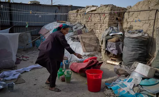 Sima sorts through items in the backyard of her home in Kabul, Afghanistan, Friday, Aug. 14, 2026. (AP Photo/Nava Jamshidi)