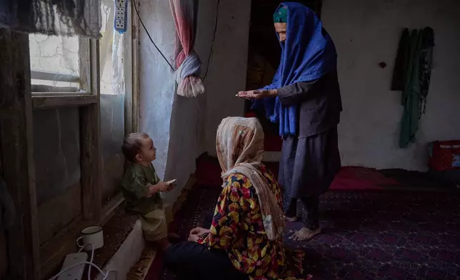 Sima plays with a young child from her extended family as the child's mother sits nearby at their home in Kabul, Afghanistan, Wednesday, Aug. 12, 2026. (AP Photo/Nava Jamshidi)