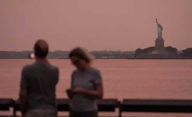 FILE - The Statue of Liberty is visible through haze due to Canadian wildfire smoke during sunset Aug. 5, 2025, in New York. (AP Photo/Yuki Iwamura, File)