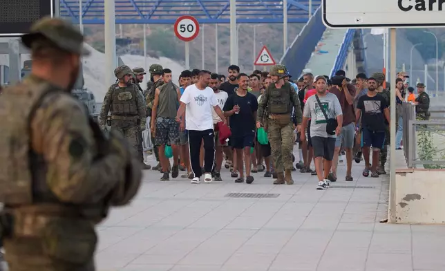 Escorted by the Spanish army, migrants who crossed into Spain return to Morocco from the Spanish enclave of Ceuta on Saturday, Aug. 1, 2026. (AP Photo/Antonio Sempere)