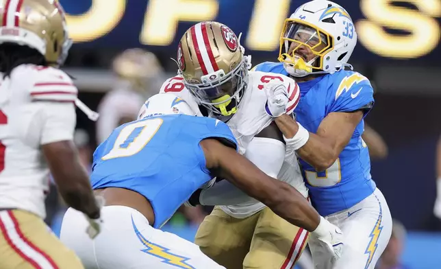 San Francisco 49ers wide receiver Deebo Samuel Sr., middle, is tackled by Los Angeles Chargers linebacker Daiyan Henley (0) and defensive back Deane Leonard (33) during the first half of a preseason NFL football game, Thursday, Aug. 20, 2026, in Inglewood, Calif. (AP Photo/Ryan Sun)