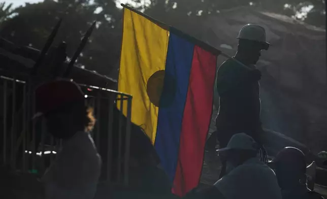 A firefighter working on rescue efforts holds a Colombian flag amid the rubble three days after an earthquake struck Cali, Colombia, Thursday, Aug. 13, 2026. (AP Photo/Ivan Valencia)