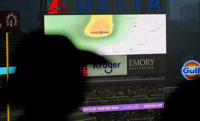Spectators watch the field during a rain delay in the third inning of a baseball game between the Atlanta Braves and the Miami Marlins, Thursday, Aug. 6, 2026, in Atlanta. (AP Photo/Mike Stewart)