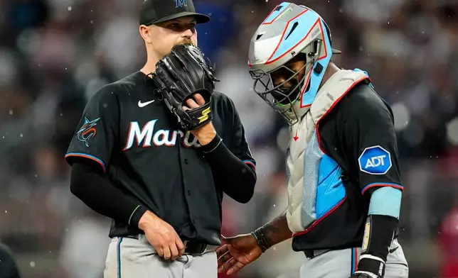 Miami Marlins pitcher Janson Junk (26) speaks with catcher Brian Navarreto in the third inning of a baseball game against the Atlanta Braves, Thursday, Aug. 6, 2026, in Atlanta. (AP Photo/Mike Stewart)