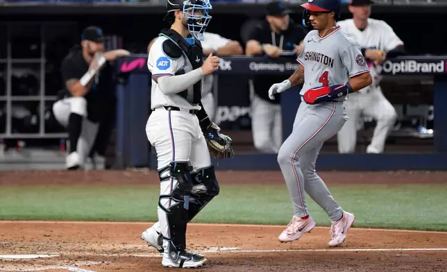 Washington Nationals' Daylen Lile scores in front of Miami Marlins catcher Joe Mack during the fifth inning of a baseball game, Saturday, Aug. 22, 2026, in Miami. (AP Photo/Michael Laughlin)