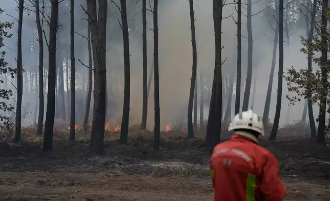 A firefighter works to extinguish a fire, near Blagon, southwestern France, Friday, July 31, 2026. (AP Photo/Baz Ratner)