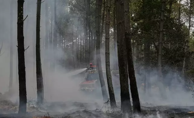 Firefighters work to extinguish a fire, near Blagon, southwestern France, Friday, July 31, 2026. (AP Photo/Baz Ratner)