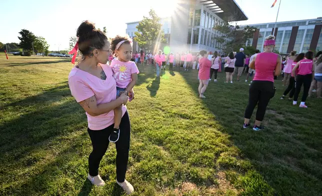 Mandie Reibold carries Michelle Martinez, 1, both of York, Pa., during a demonstration in support of Lindsay Clancy, who is on trial in connection with the deaths of her three children, outside Plymouth Superior Court on Thursday, Aug. 20, 2026, in Plymouth, Mass. (AP Photo/Josh Reynolds )