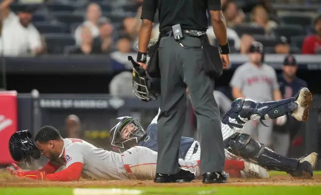 Boston Red Sox' Ceddanne Rafaela is tagged out by New York Yankees catcher Austin Wells at home plate on a double play during the seventh inning of a baseball game, Friday, Aug. 28, 2026, in New York. (AP Photo/Yuki Iwamura)