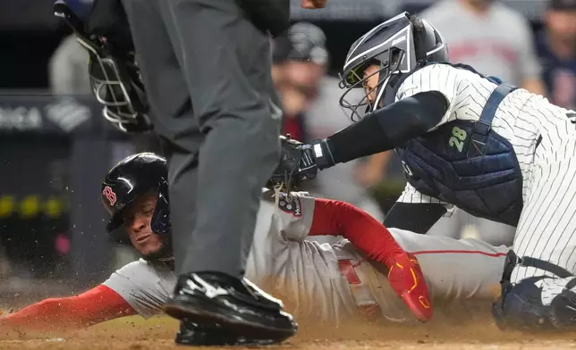 Boston Red Sox' Ceddanne Rafaela is tagged out by New York Yankees catcher Austin Wells at home plate on a double play during the seventh inning of a baseball game, Friday, Aug. 28, 2026, in New York. (AP Photo/Yuki Iwamura)