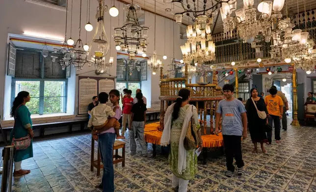 Tourists visit the main hall adorned with 19th-century Belgian crystal chandeliers and colorful glass lanterns at the 458-year-old Paradesi Synagogue in the historic Jew Town neighborhood of Kochi, India, Wednesday, May 20, 2026. (AP Photo/Aijaz Rahi)