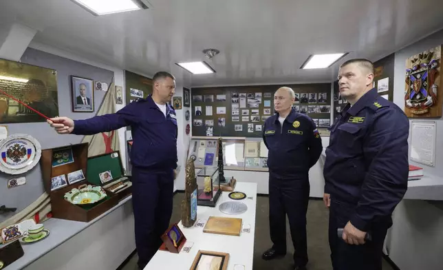 Russian President Vladimir Putin, center, listens to a navy officer as he visits the Varyag missile cruiser of the Pacific Fleet to watch a military exercise near Yuzhno-Sakhalinsk, on Sakhalin Island, Russia, Wednesday, Aug. 12, 2026, as Admiral Viktor Liina, right, looks on. (Gavriil Grigorov, Sputnik, Kremlin Pool Photo via AP)