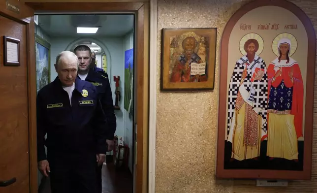 Russian President Vladimir Putin visits the Varyag missile cruiser of the Pacific Fleet to watch a military exercise near Yuzhno-Sakhalinsk, on Sakhalin Island, Russia, Wednesday, Aug. 12, 2026, as Admiral Viktor Liina follows him. (Gavriil Grigorov, Sputnik, Kremlin Pool Photo via AP)