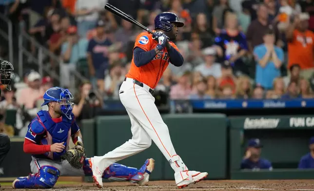 Houston Astros' Yordan Alvarez, right, hits a two-run single in front of Texas Rangers catcher Austin Wynns during the second inning of a baseball game Friday, July 31, 2026, in Houston. (AP Photo/David J. Phillip)